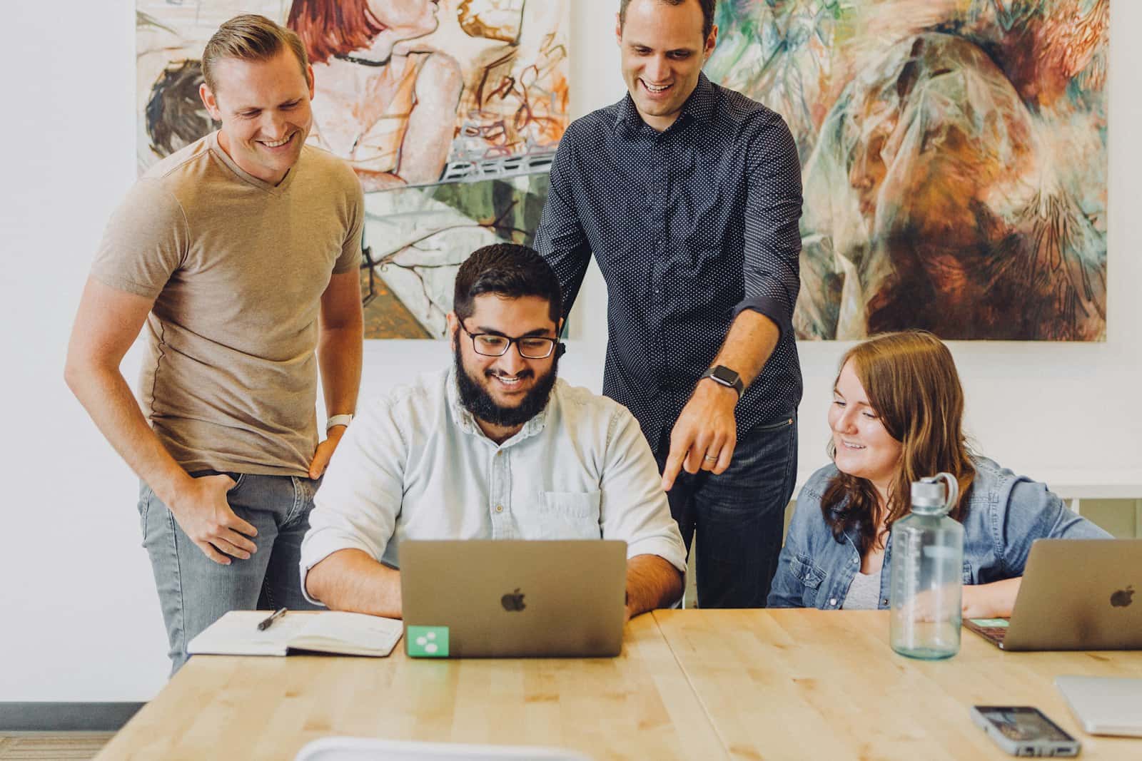 Four coworkers around a laptop at a table