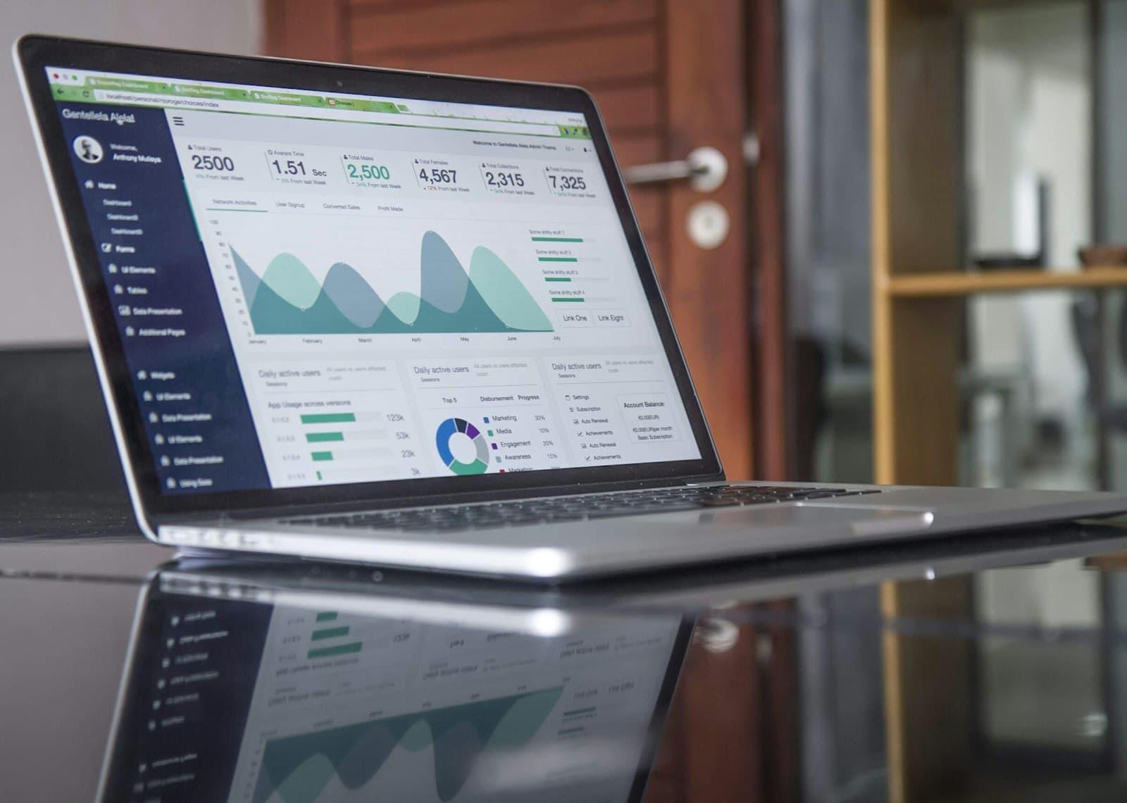 A laptop with charts on a glass-top table