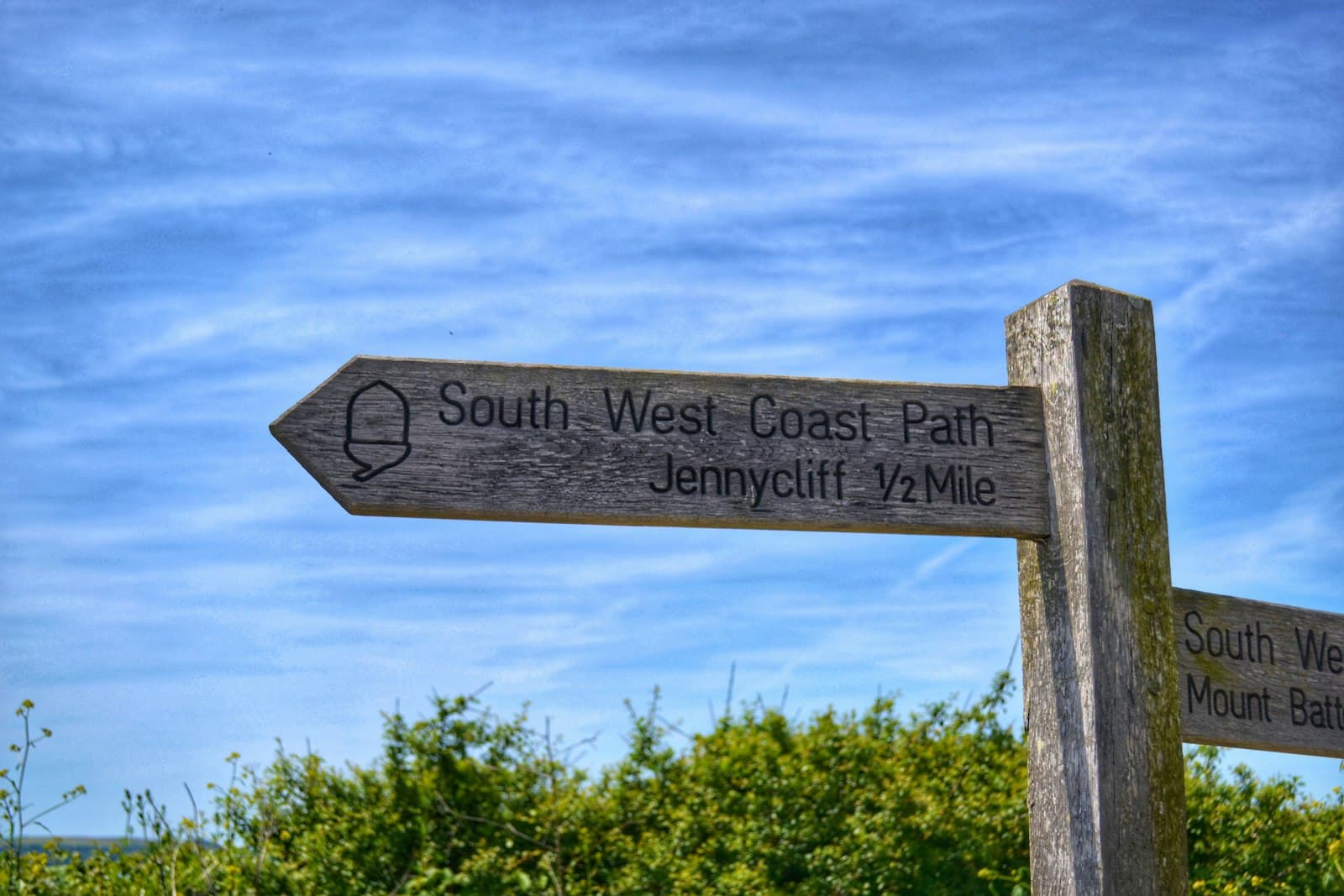 A wooden signpost on the South West Coast Path pointing two ways