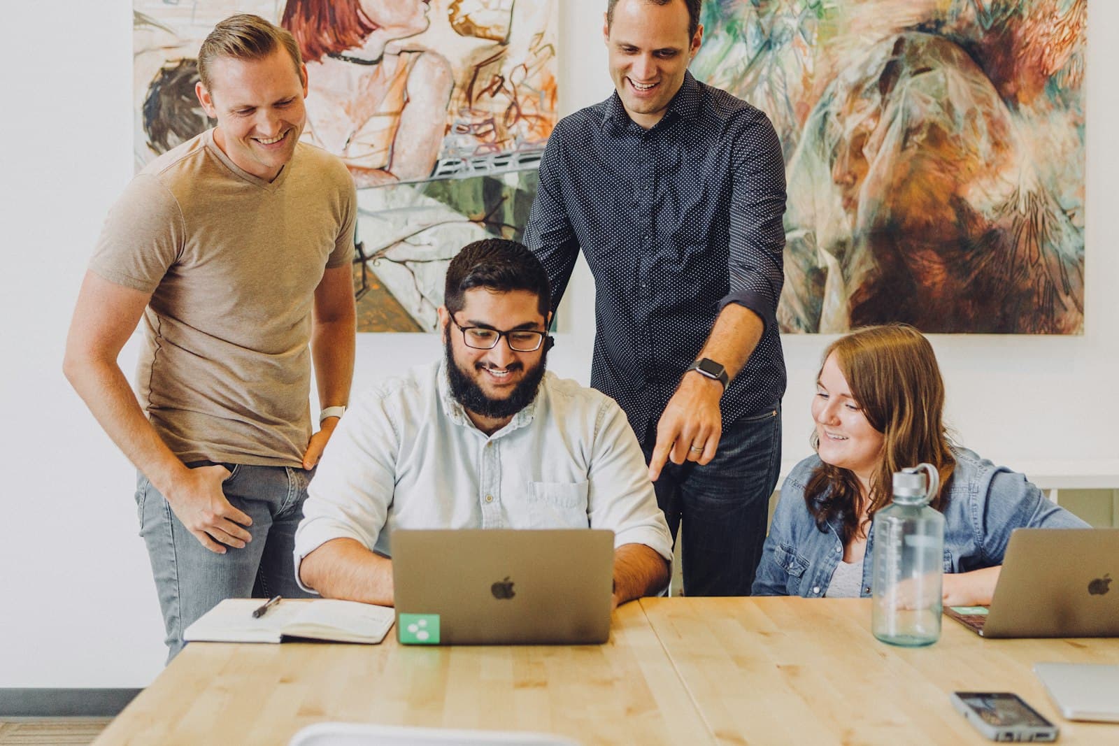 Four coworkers around a laptop at a table