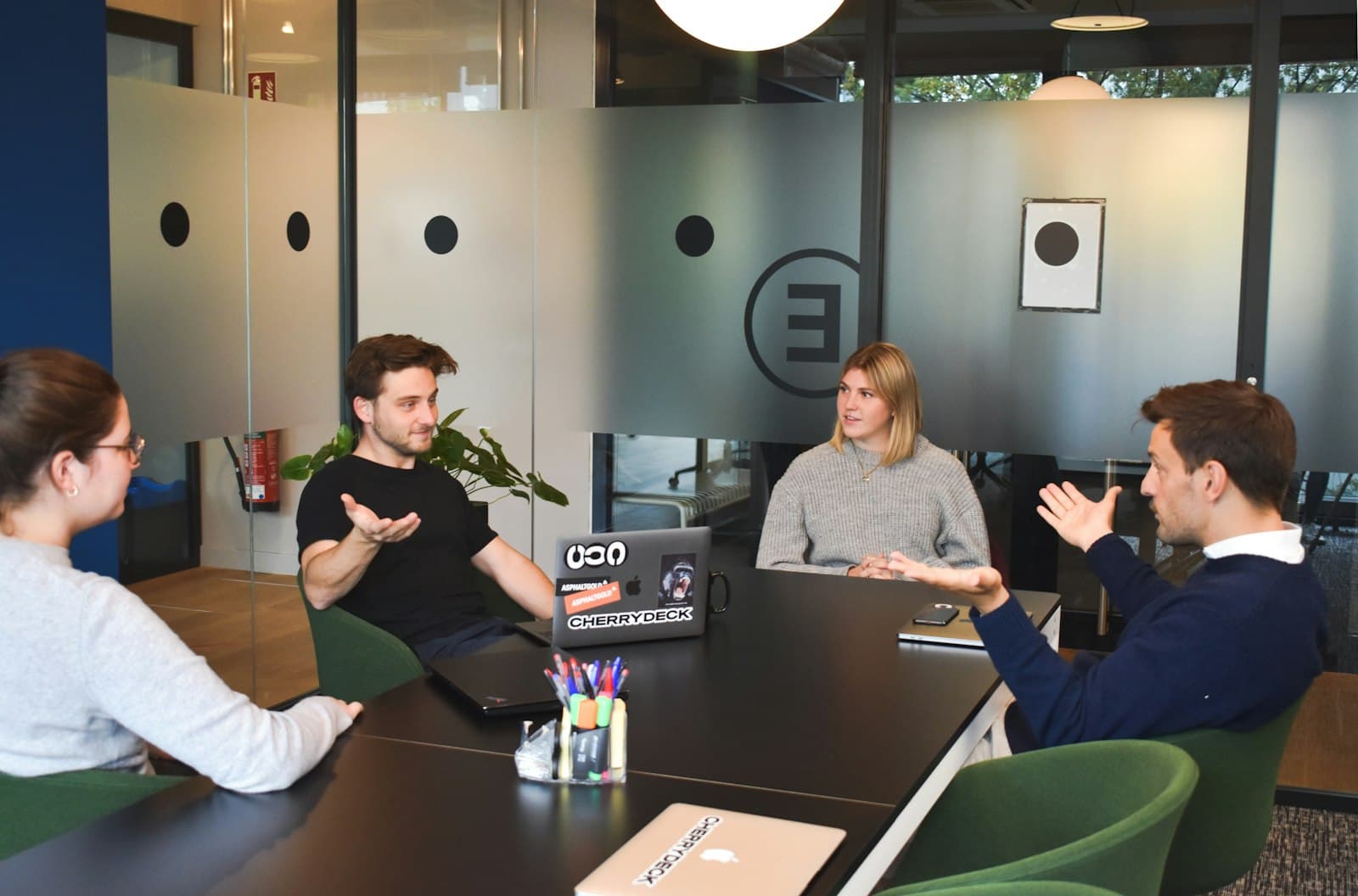 Four people in a meeting around a black table in a modern office